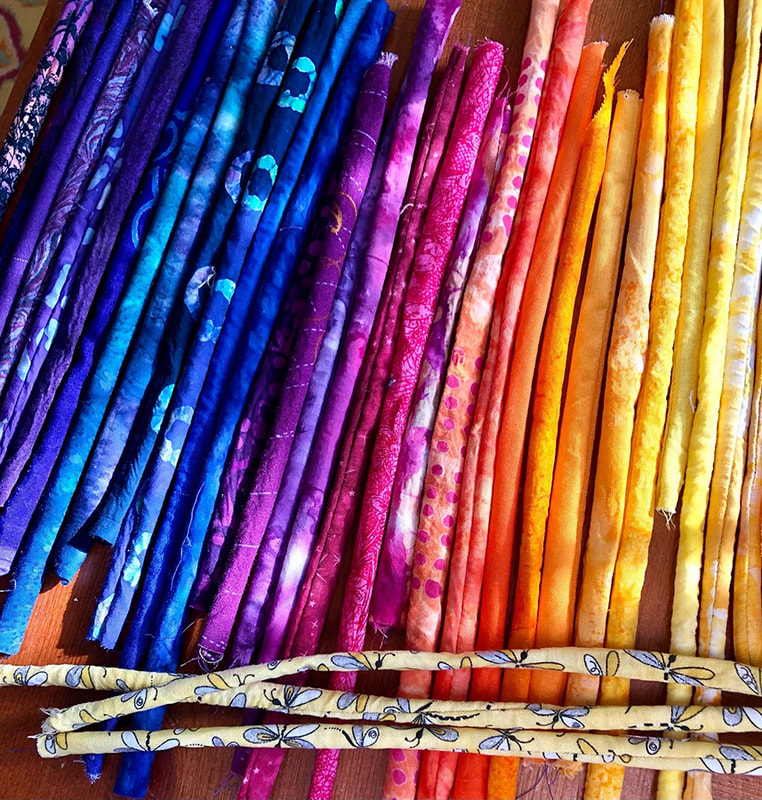 Little tubes of fabric laid out in rainbow order from purple to yellow